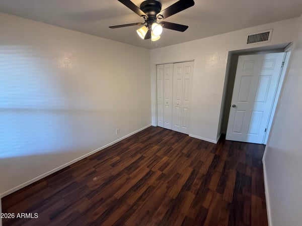 Comfortable bedroom featuring a ceiling fan, large closet, and attractive wood-look flooring. The spacious layout provides flexibility for bedroom furnishings while maintaining a bright and inviting atmosphere.