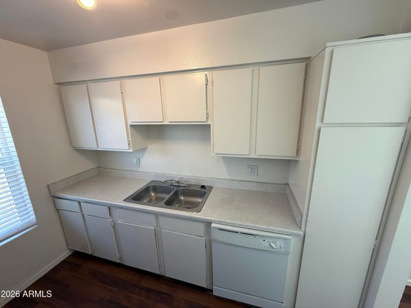 Well-appointed kitchen with dual-basin sink, dishwasher, and ample cabinet storage. Large windows enhance the space with natural light while creating an inviting environment for meal preparation.