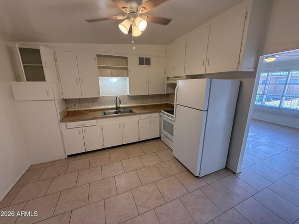 Functional kitchen featuring extensive cabinetry, generous work surfaces, double sink, and included appliances. Ideal for daily cooking, meal prep, and convenient storage organization.