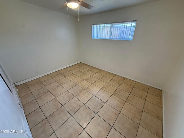 Secondary bedroom with natural light, ceiling fan, and low-maintenance tile flooring. Perfect as a guest room, home office, exercise room, or additional living space.