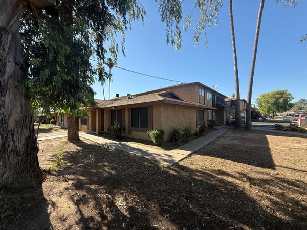 Beautiful exterior perspective highlighting towering shade trees, pedestrian walkways, and a well-maintained residential environment. Residents enjoy a convenient location near shopping, dining, and recreation.