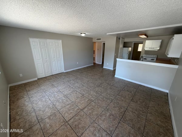 Large open living area with durable tile flooring, neutral color palette, and seamless flow to the kitchen. The versatile layout offers excellent space for entertaining and daily living.