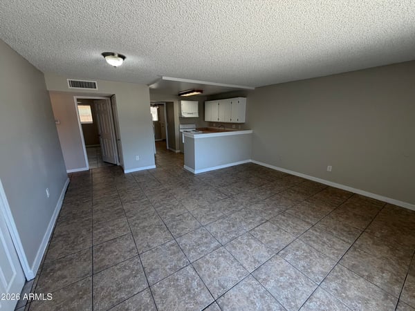 Open-concept living room featuring expansive floor space, low-maintenance finishes, and easy access to the kitchen. Ideal for comfortable living and entertaining guests.