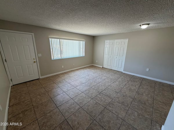 Bright living room with large picture window, neutral paint, and attractive tile flooring. Natural light enhances the welcoming atmosphere throughout the home's central gathering space.