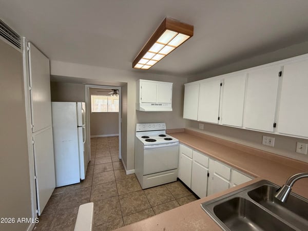 Functional kitchen offering abundant cabinetry, extended countertops, refrigerator, electric range, and practical workspace. Designed for convenience and everyday usability.