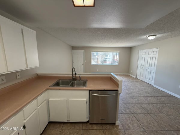 Kitchen overlooking the living area with breakfast bar, dual sink, ample storage, and included appliances. The open design supports both entertaining and daily family interaction.