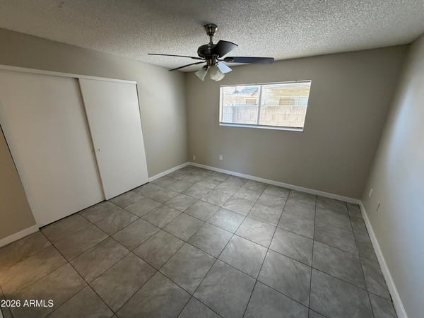 Well-sized bedroom featuring tile flooring, ceiling fan, natural light, and closet storage. A versatile space suitable for guests, family members, or a dedicated workspace.