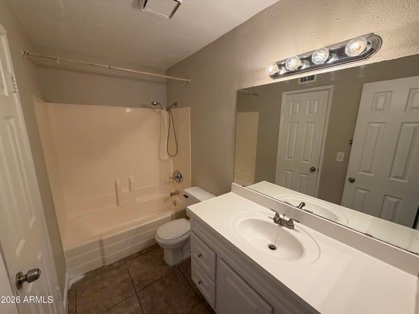 Well-maintained bathroom showcasing a large vanity, oversized mirror, tub and shower combination, and abundant lighting. Functional design and easy-care finishes enhance everyday convenience.