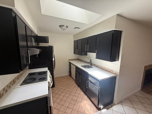 Bright kitchen with extensive cabinet storage, ample countertop workspace, and overhead natural lighting. The efficient layout supports both everyday meal preparation and entertaining needs.