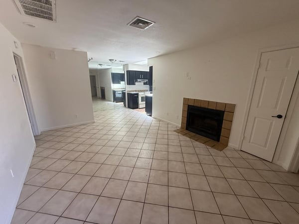 Generously sized living room featuring tile flooring, neutral tones, and a fireplace centerpiece. The flexible floor plan allows for multiple seating arrangements and comfortable daily living.