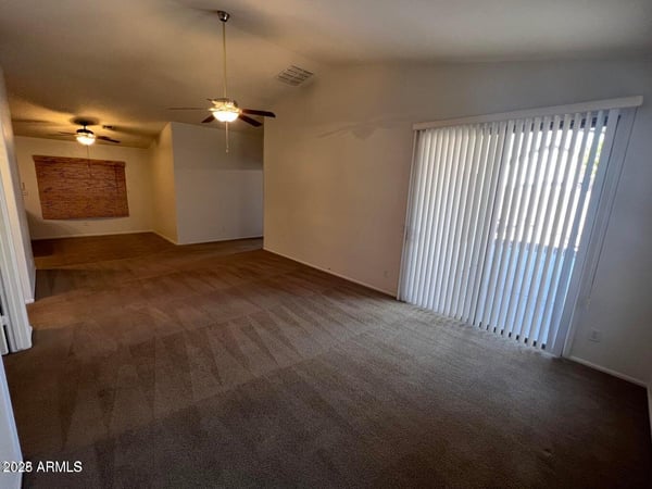 Large living room with vaulted ceilings, soft neutral finishes, and sliding glass doors that bring natural light indoors. This versatile space is ideal for entertaining guests or enjoying everyday relaxation.