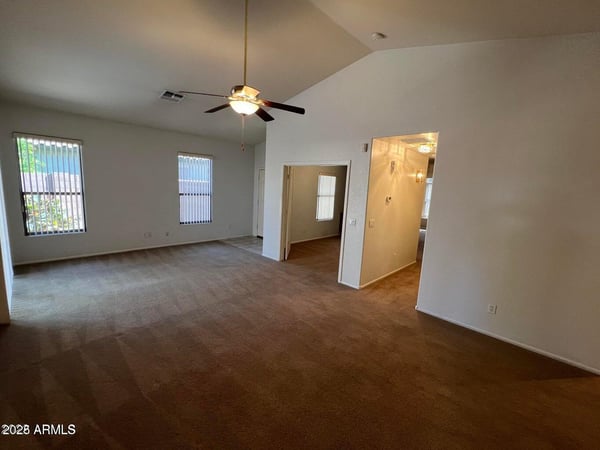 Bright and spacious living room offering vaulted ceilings, multiple windows, and flexible furniture placement options. The open layout enhances comfort while maximizing usable living space.