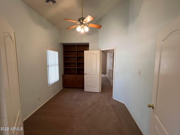 Flexible den enhanced by custom built-in shelving and vaulted ceilings. Ideal as a home office, study area, reading room, or hobby space while adding versatility to the home's layout.