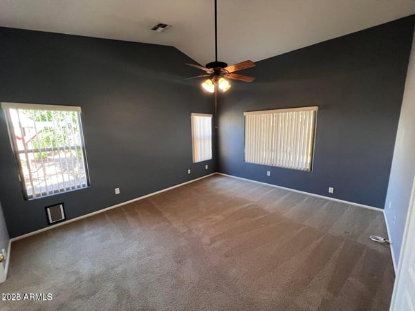 Generously sized primary bedroom with vaulted ceilings, ceiling fan, and abundant natural light. The spacious design creates a private retreat that balances comfort and functionality.