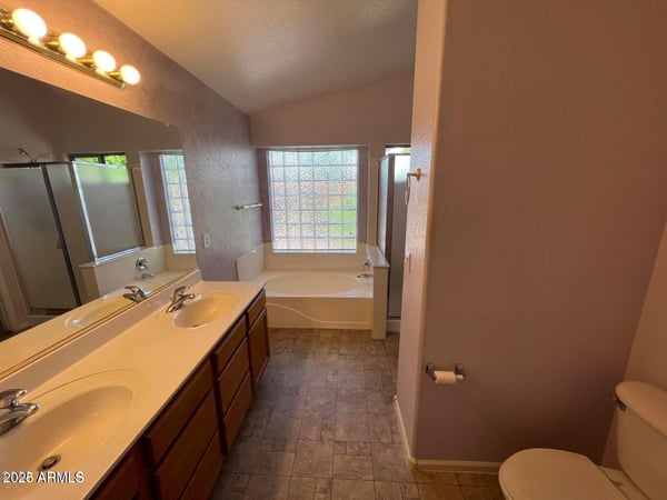 Generous primary bathroom featuring dual vanities, extensive countertop space, a soaking tub, and separate shower. A well-designed space that balances style and everyday practicality.