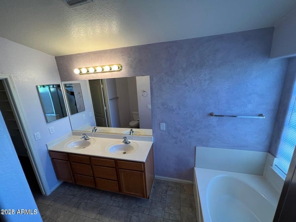 Spacious bathroom showcasing dual sinks, abundant cabinetry, and a large soaking tub. The open layout and natural light create an inviting atmosphere for daily routines.