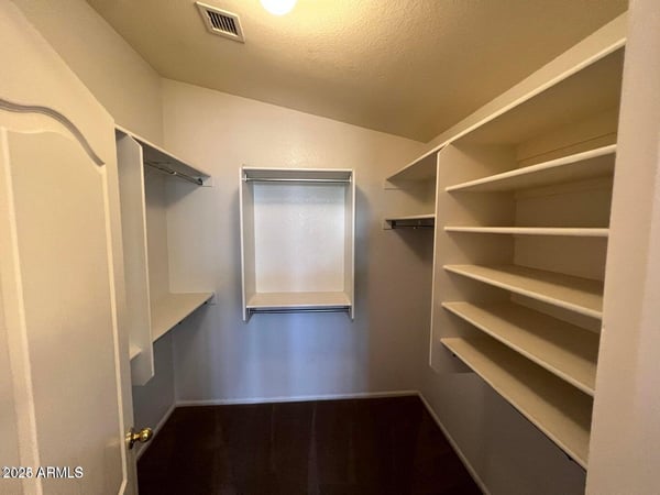 Large walk-in closet complete with built-in shelving and multiple hanging sections. Ideal for keeping clothing, shoes, and accessories neatly organized and easily accessible.