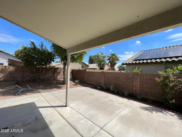 Covered patio offering shade and views of the landscaped backyard. The generous outdoor living area is ideal for entertaining, dining, or simply enjoying the peaceful surroundings of this Goodyear property.