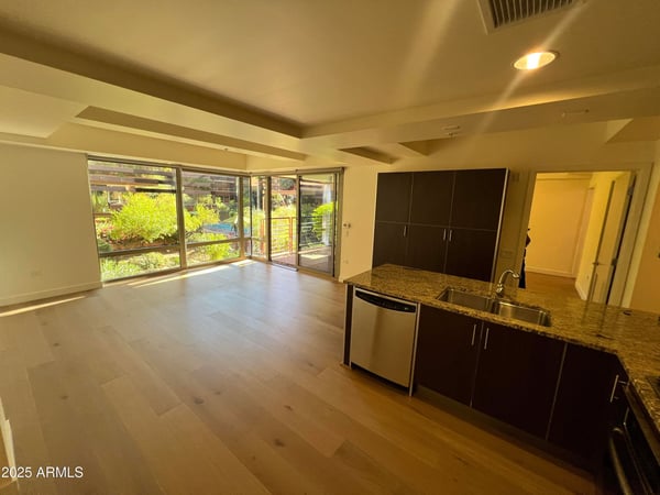 Spacious great room with elegant wood flooring and flexible furniture placement options. Large windows provide natural light while showcasing attractive community landscaping.