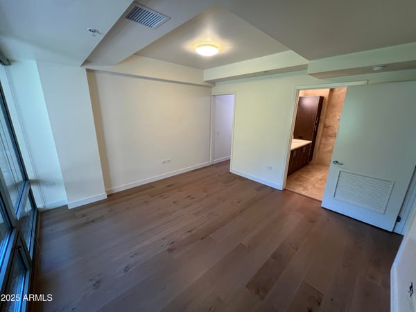 Spacious bedroom offering wood flooring, large windows, and a tranquil atmosphere. Convenient access to the walk-in closet and bathroom enhances everyday comfort.