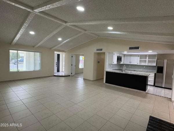 Light-filled great room seamlessly connected to the kitchen and surrounding living spaces. The vaulted ceiling design enhances openness and visual appeal throughout the home.