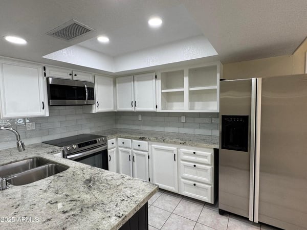 Updated kitchen featuring granite countertops, stainless steel appliances, refreshed cabinetry, and a modern tile backsplash. Designed to combine style, storage, and functionality.