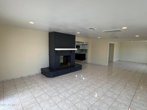 Open-concept family room showcasing a statement fireplace and seamless connection to the kitchen. The spacious design supports comfortable daily living and effortless entertaining.