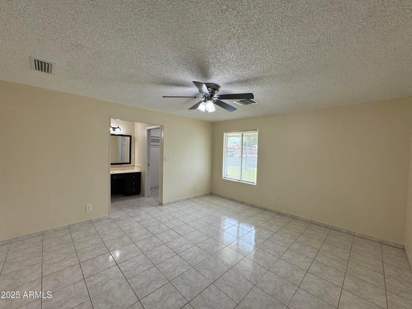 Large primary suite with room for oversized furnishings, ceiling fan, and private bathroom access. A comfortable retreat designed for relaxation and convenience.