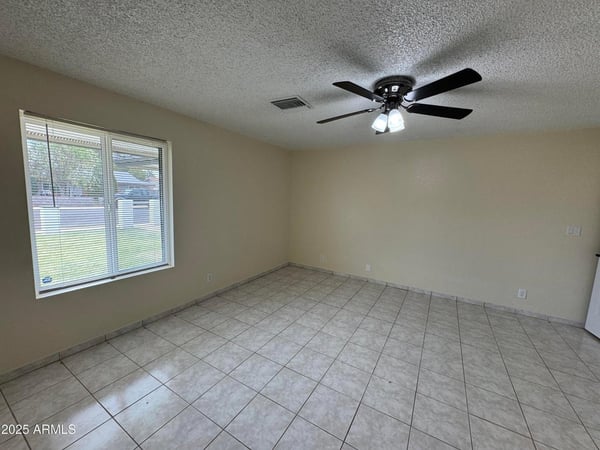 Expansive primary bedroom featuring tile flooring, a ceiling fan, and large windows that provide natural light throughout the day. This comfortable retreat