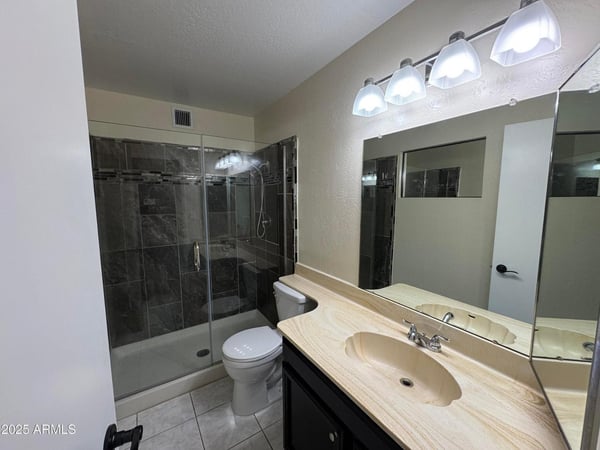 Beautifully upgraded primary bathroom highlighted by a custom tile walk-in shower with glass enclosure, modern lighting, and extended vanity space. Quality updates create a spa-inspired atmosphere.