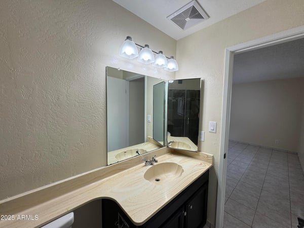 Well-designed primary bathroom featuring an oversized vanity, updated light fixtures, and abundant counter space. The functional layout provides comfort and convenience for daily routines.