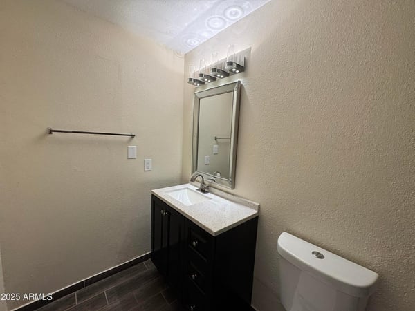 Updated half bathroom featuring contemporary fixtures, a sleek vanity, upgraded lighting, and attractive flooring. This refreshed space adds convenience and modern appeal to the home.