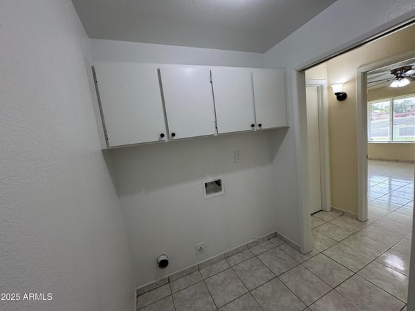 Convenient laundry room with overhead cabinetry, dedicated utility connections, and space for storage solutions. Designed to simplify daily household tasks while maximizing organization.