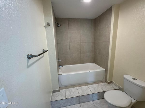 Well-sized bathroom featuring a tub and shower combination with updated tile surround and practical layout. Designed to provide comfort, convenience, and easy maintenance.