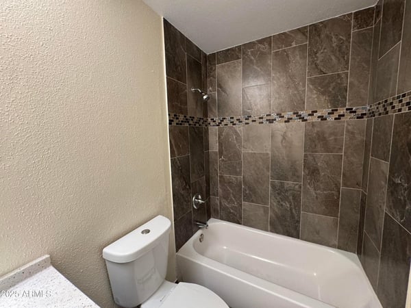 Attractive guest bathroom showcasing a stylish tile tub surround with decorative accent details and updated finishes. The refreshed design offers durability and timeless appeal.