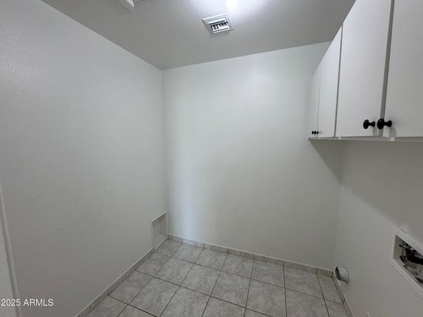Spacious utility and laundry area featuring built-in cabinetry, durable tile flooring, and plenty of room for storage. A practical addition that supports organized living.