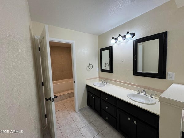 Well-appointed bathroom showcasing a double vanity, updated fixtures, abundant counter space, and tile flooring. Designed for everyday convenience, this space supports busy households and visiting guests alike.