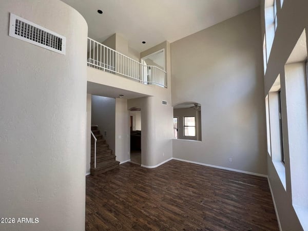 The impressive two-story living room showcases soaring ceilings, abundant sunlight, and beautiful wood-look flooring. The spacious design provides a bright and open environment ideal for entertaining and everyday living.