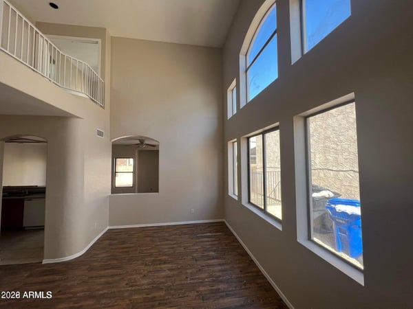 Large picture windows and impressive ceiling heights create a bright and inviting gathering space. This open-concept living area offers flexibility for furniture arrangements and comfortable everyday living.
