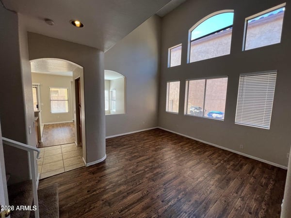 Tall ceilings and expansive windows create a bright, airy living space filled with natural light. The open floor plan and stylish flooring make this room perfect for entertaining and everyday comfort.