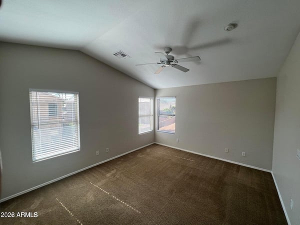 This inviting owner's suite features large windows, elevated ceilings, and plenty of room for a sitting area or additional furnishings. Natural light enhances the warm and comfortable atmosphere.
