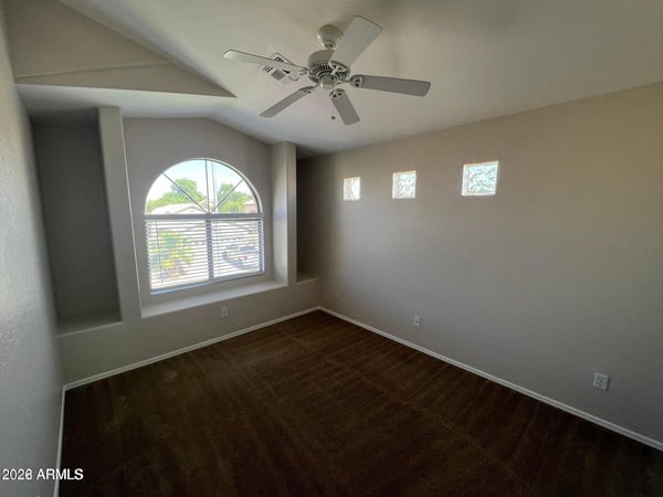 Distinctive architectural details, including an arched window and decorative glass accents, add character to this upstairs bedroom. Natural light and attractive flooring complete the space.