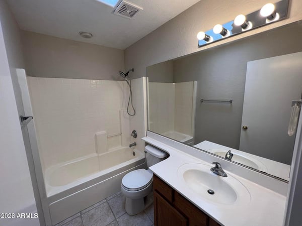 Brightened by a skylight, this full bathroom includes a tub and shower combination, vanity storage, and durable finishes. The clean design complements the home's comfortable layout.
