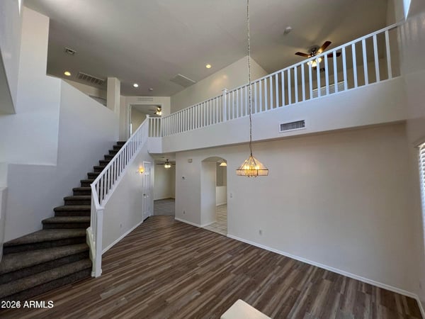 Soaring ceilings and expansive windows fill this open living room with natural light. Updated flooring and an open-concept layout create a bright, airy space designed for modern living.