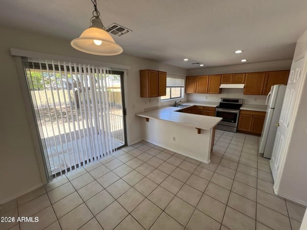 Featuring ample cabinetry, durable tile flooring, and a breakfast bar, this kitchen combines functionality with convenience. The open dining area creates an ideal space for daily living.