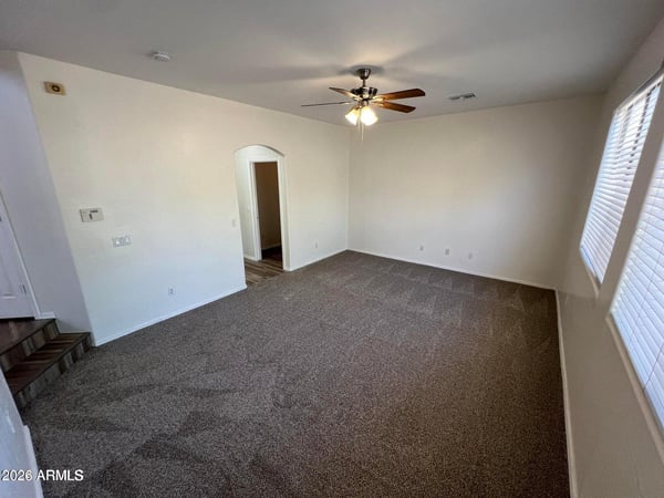 Spacious primary bedroom with soft carpeting, neutral color palette, and plenty of room for oversized furnishings. The comfortable layout creates a relaxing owner's retreat.