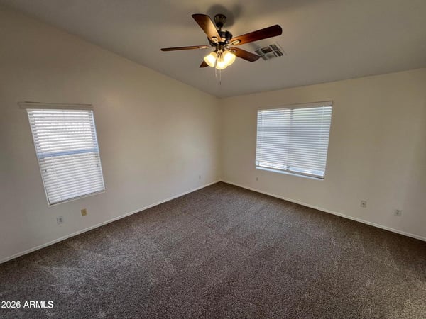 Bright secondary bedroom with plush carpeting, ceiling fan, and large windows that fill the room with natural light. Perfect for guests, family members, or a home office setup.