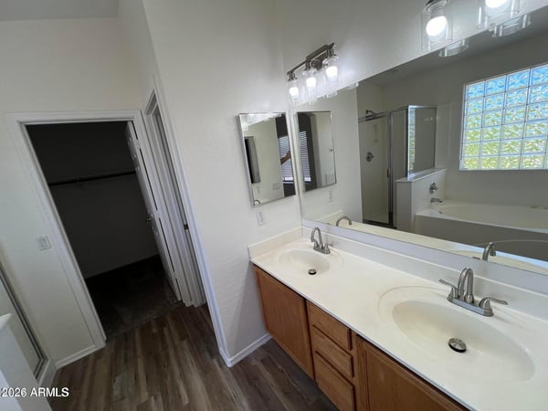 Elegant primary bathroom showcasing dual sinks, expansive counter space, updated fixtures, and a bright open design. The layout offers convenience and comfort for daily routines.