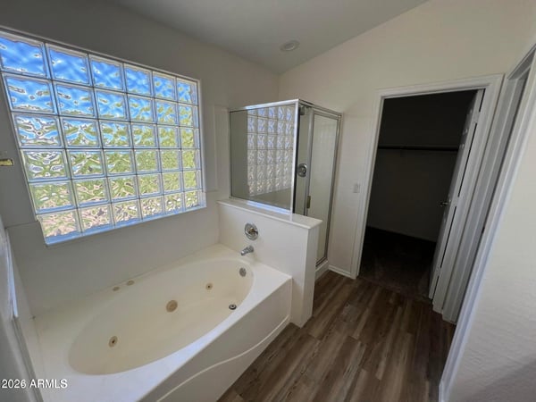 Enjoy a spa-like atmosphere with a soaking tub, separate shower, and natural light filtering through decorative glass block windows. A relaxing retreat within the primary suite.