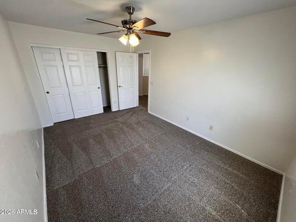 Secondary bedroom featuring soft carpeting, ceiling fan, closet storage, and natural light. The clean, neutral design allows for easy personalization.